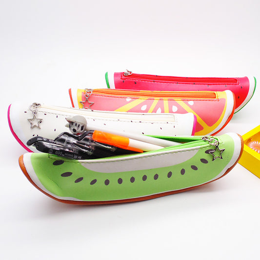 Three plush fruit pencil cases—green kiwi front, white and pink behind; front open with pens and star charm.