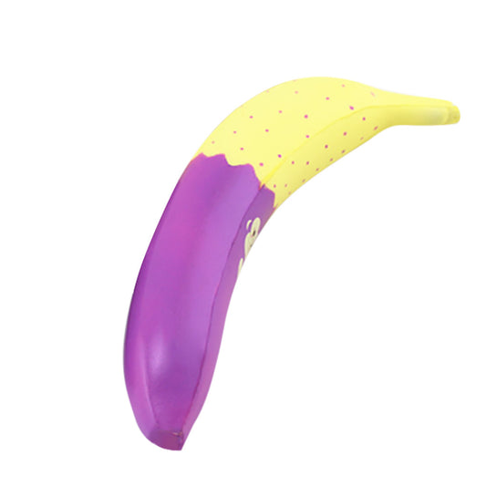 Monkey Noodle Banana squishy charm curved on a white background, yellow with pink dots and a purple base
