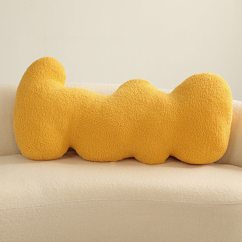 Single yellow teddy-textured knotted cushion with bulbous segments resting on a cream sofa.