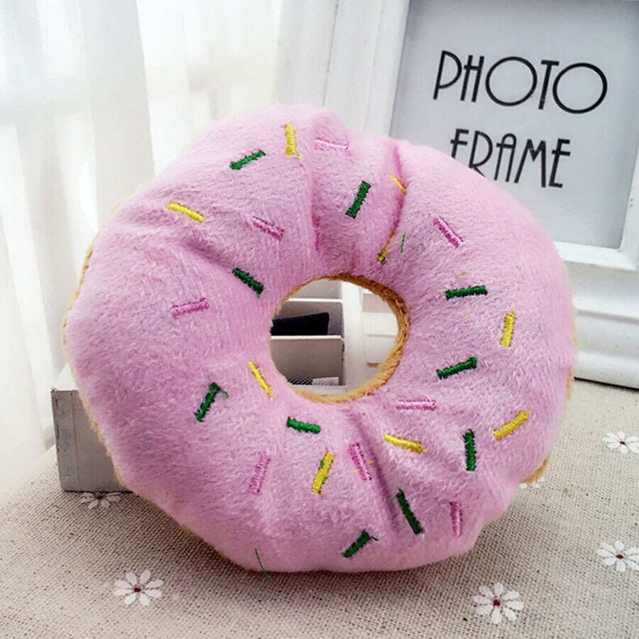 Pink plush donut pet toy with embroidered sprinkles standing up