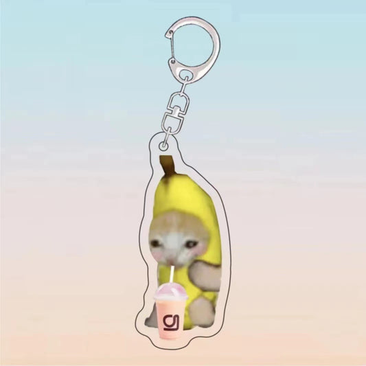 Kawaii banana cat keychain featuring a cat in a banana costume sipping a milkshake, with a silver chain and clip.