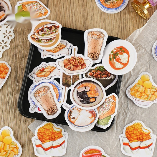 17 colorful food stickers on a black tray and wood table showing bubble tea, dumplings, skewers and fries.