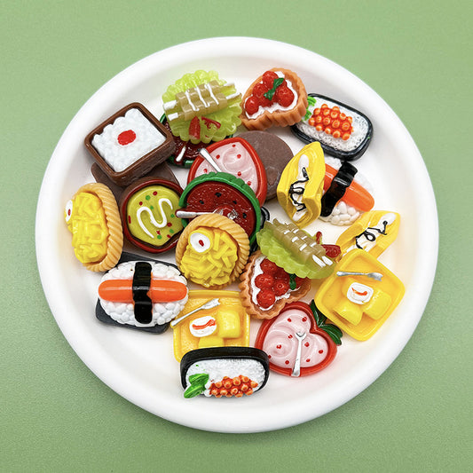 Plate of miniature food fridge magnets including sushi, cakes and tarts on green