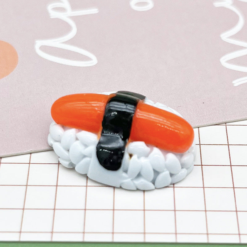 One glossy miniature sushi magnet: white textured rice, bright orange fish slice and black seaweed band.