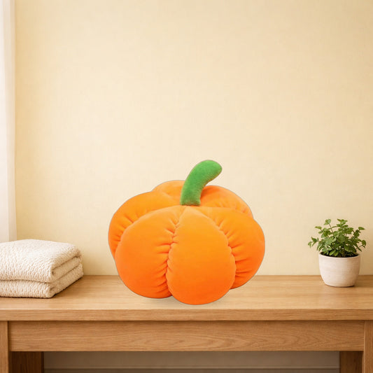 Orange pumpkin plush toy sitting on a light oak bench