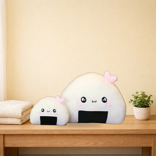 Large and small rice ball plush pillows with pink hearts on a light oak console table
