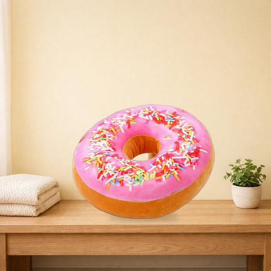 Pink Lady donut plush pillow sitting on a light oak bench