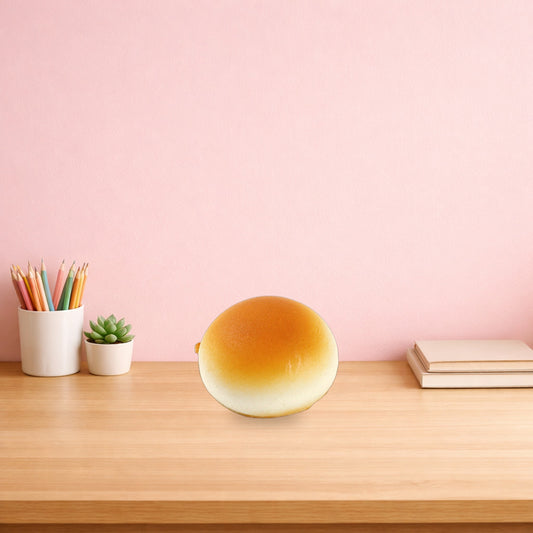 Golden glazed bun squishy on a light oak desk