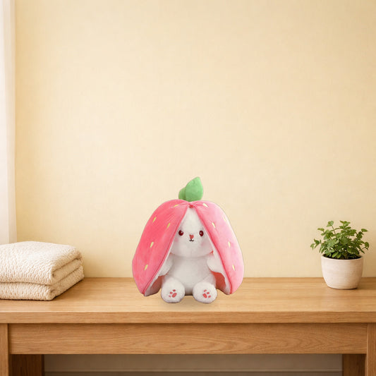 Strawberry rabbit plushie sitting on a light oak bench