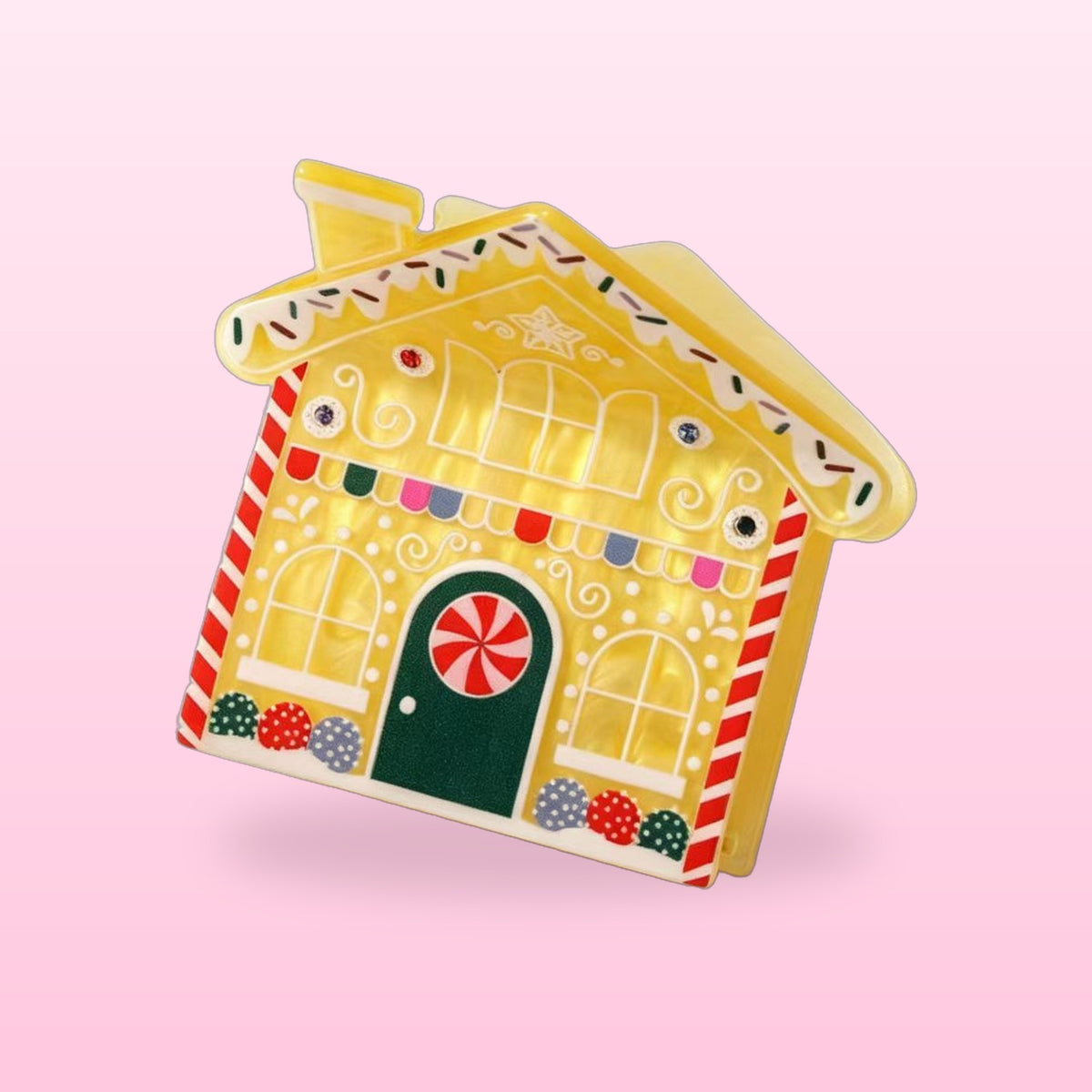 Lemon icing gingerbread house claw clip with a green door and candy cane corners on a pink background