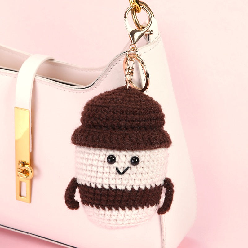 Mocha crochet coffee cup charm hanging from the handle of a pale pink handbag
