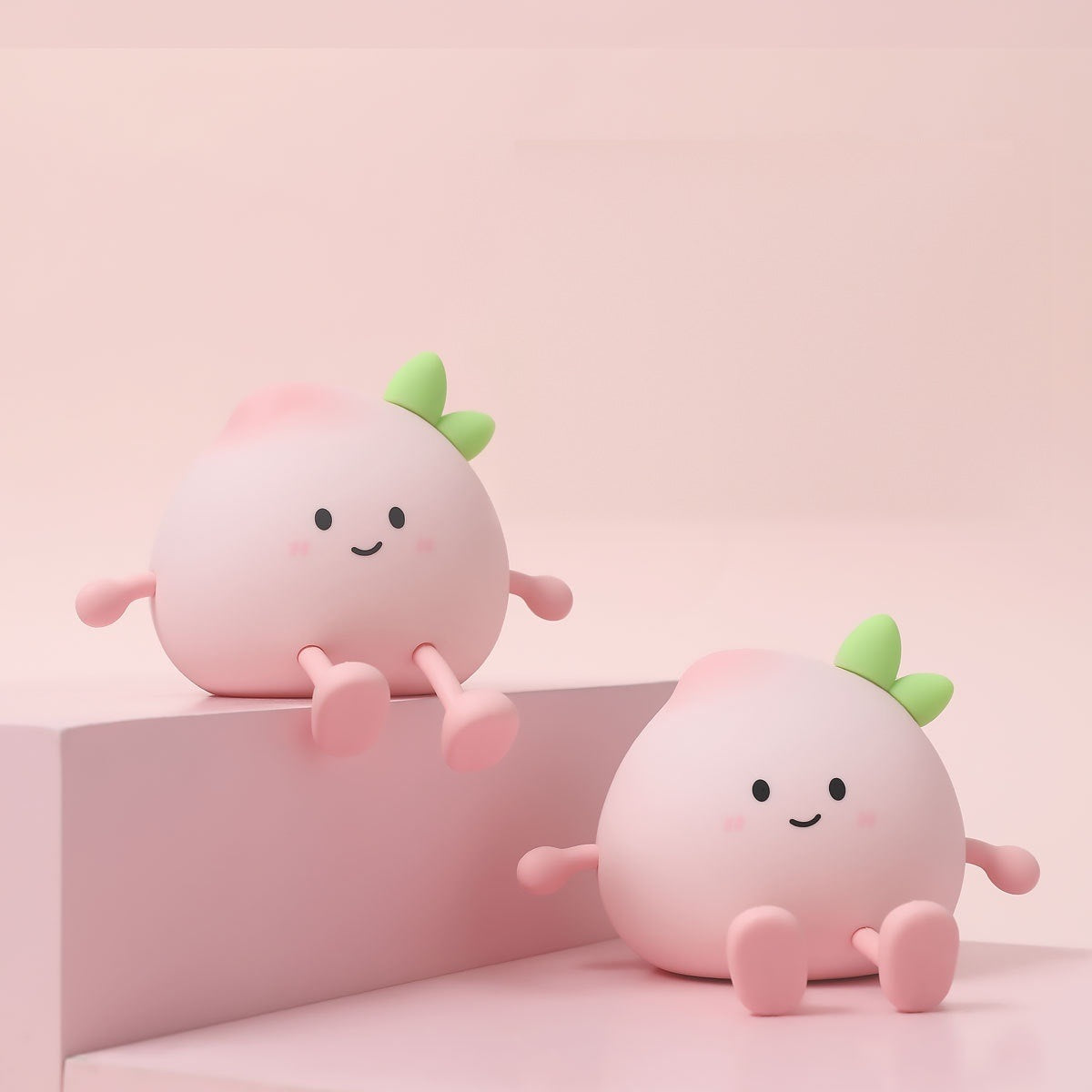 Two peach night lights switched off, one sitting on a pink step with its feet hanging over