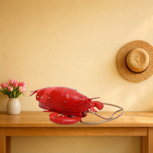Red lobster crossbody bag with its gold chain on an oak hall table