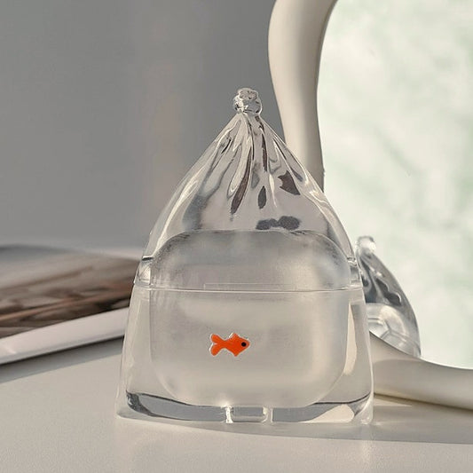 Clear goldfish in a bag AirPods case catching the light on a desk