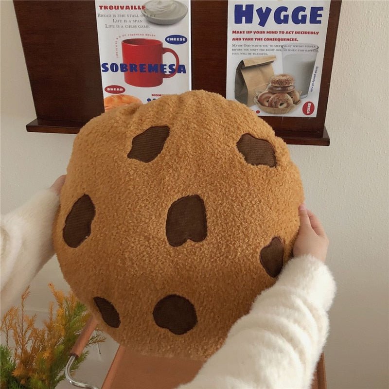 Chocolate chip cookie plush cushion held up in both hands, fluffy teddy fabric close-up