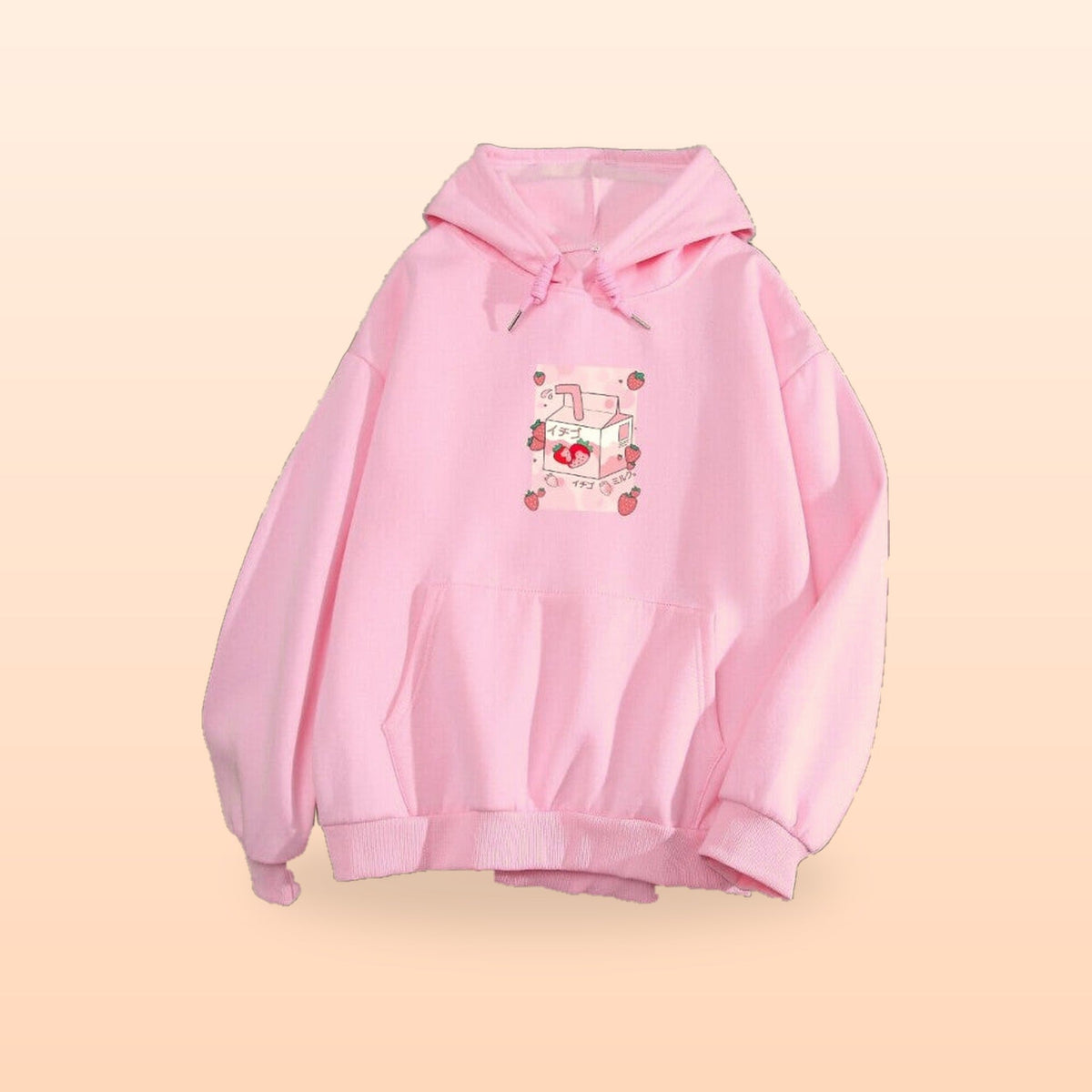 Pink strawberry milk hoodie with a strawberry milk carton graphic, laid flat on a peach background