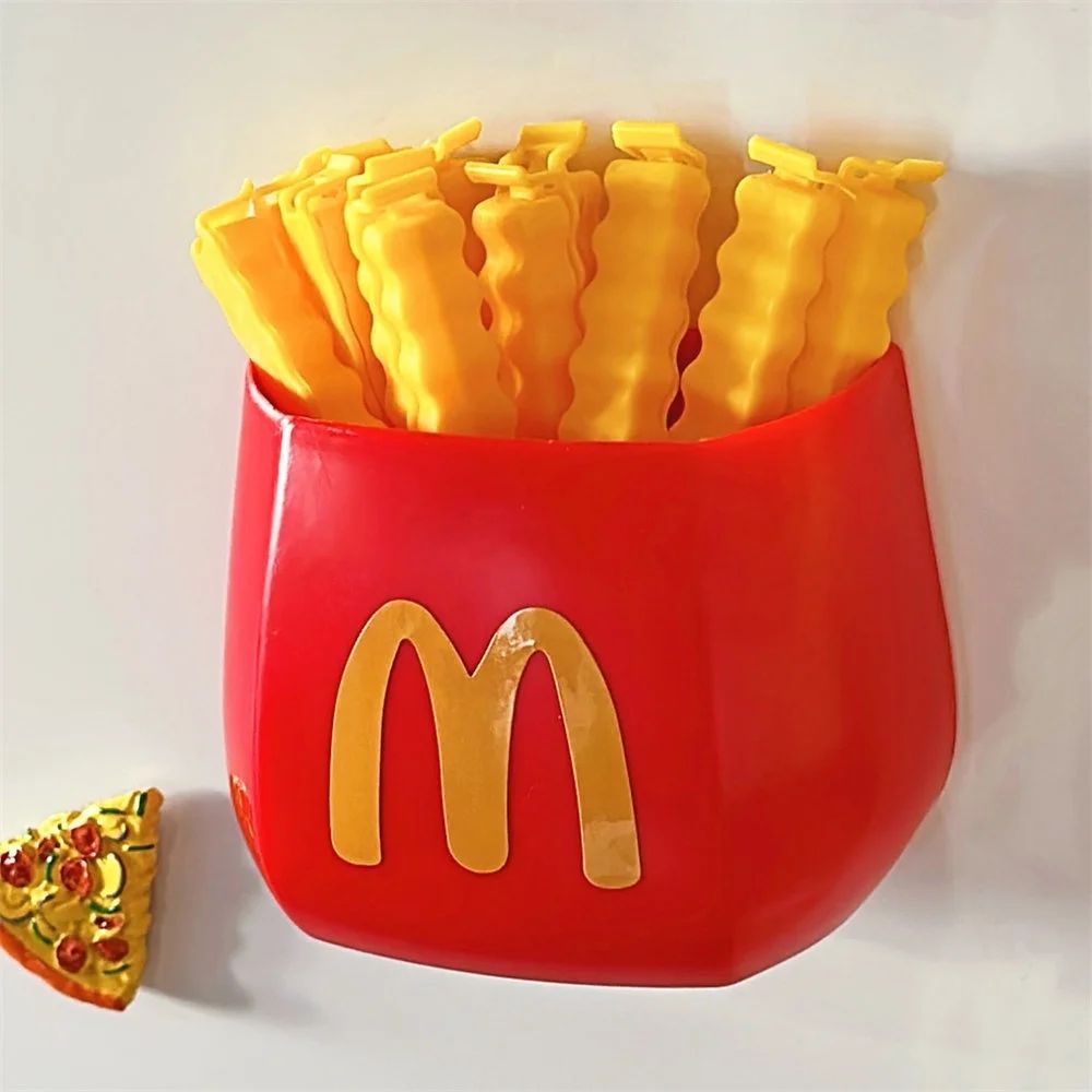 Red fries-shaped holder with gold 'M' and eight yellow wavy clips, plus one small pizza-slice magnet.