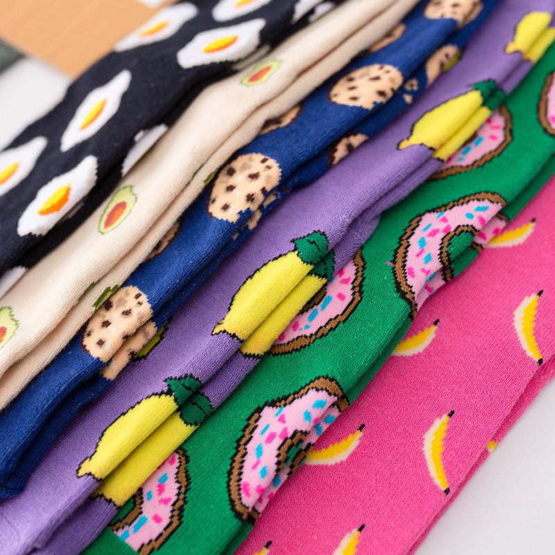 Colourful food-themed ankle socks featuring designs of eggs, avocado, donuts, and bananas in a stacked arrangement.