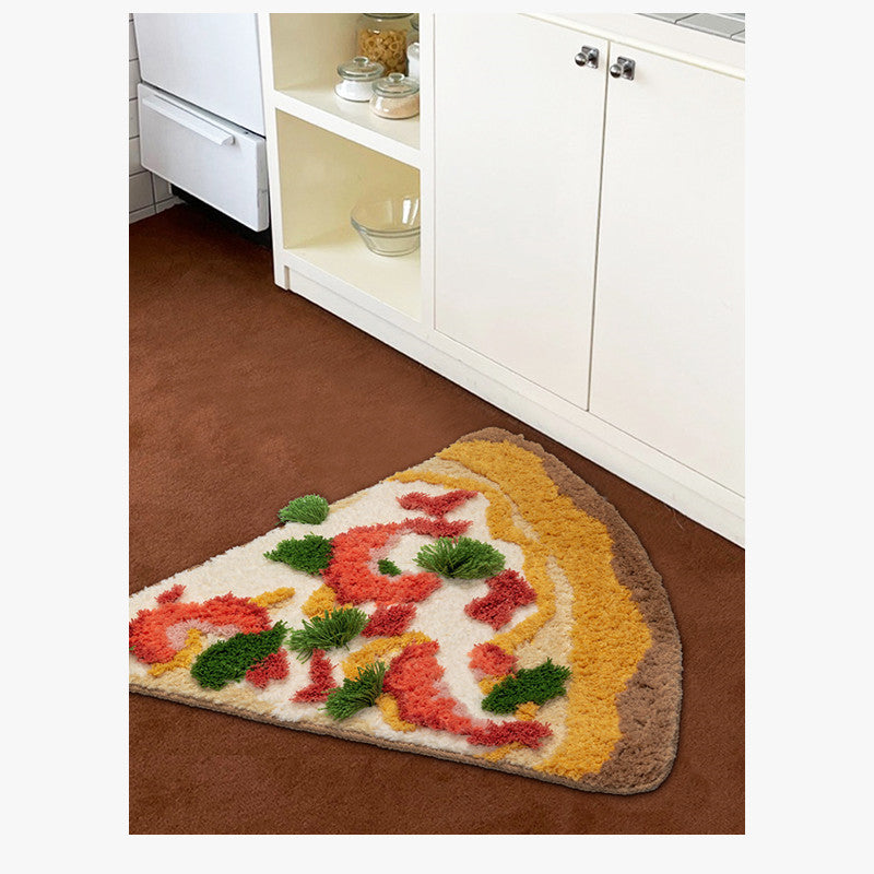 One triangular plush pizza rug: brown crust, yellow cheese, red toppings and green tufts on brown floor.