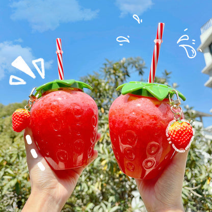 Two glossy red strawberry-shaped bottles with green leaf lids, red-and-white straws and strawberry charms.