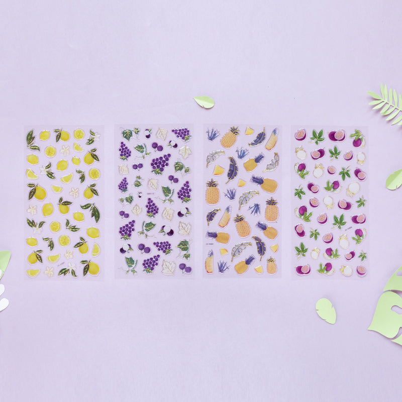 Four clear sticker sheets on lilac background showing lemons, grapes, pineapples, and purple round fruit.