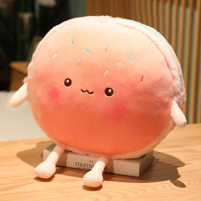 One round peach-pink plush cushion with embroidered smiling face, small arms, long legs and sprinkles.