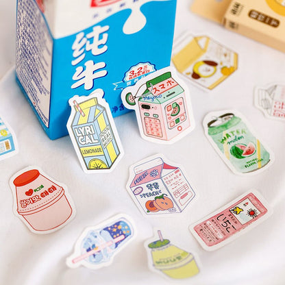 Eleven colorful drink and snack die-cut stickers on white cloth beside a partially visible blue milk carton.