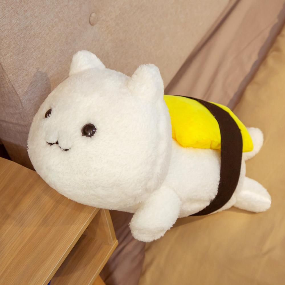 One white fluffy cat-shaped plush pillow lying on its side with a yellow topping and black strap.