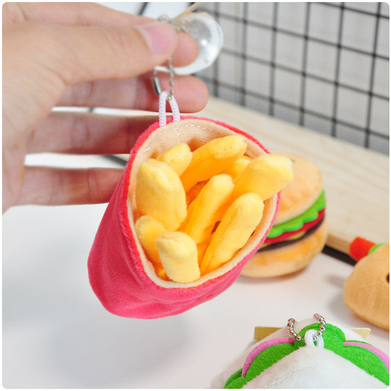 Hand holding one plush yellow french fries keychain in a pink fabric pouch with metal ring.