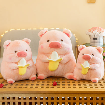 Three adorable pink pig plush toys, each holding a banana, with varying sizes on a wooden bench.