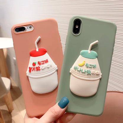 Two phone cases: one peach and one sage green, each with a 3D drink cup charm—strawberry and banana.
