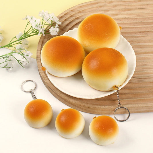 Golden bun squishy keychains on a plate and wooden board with small white flowers