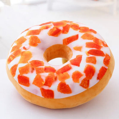 One donut-shaped plush pillow with center hole, tan base, white icing and scattered orange sprinkle patches.