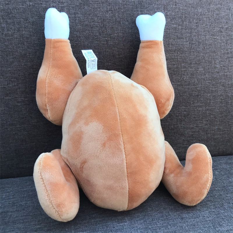 One tan roast-chicken plush with two upright drumsticks, white bone tips, and a tag on a dark gray couch.