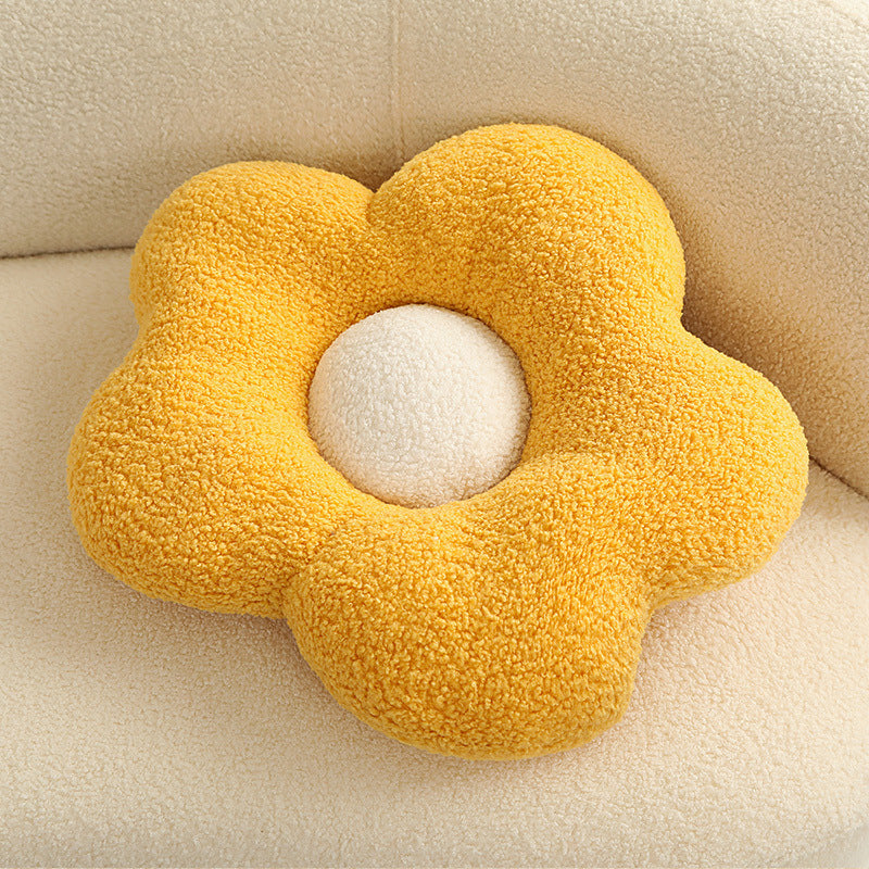 1 yellow fuzzy flower-shaped cushion with a white round center resting on a cream sofa.