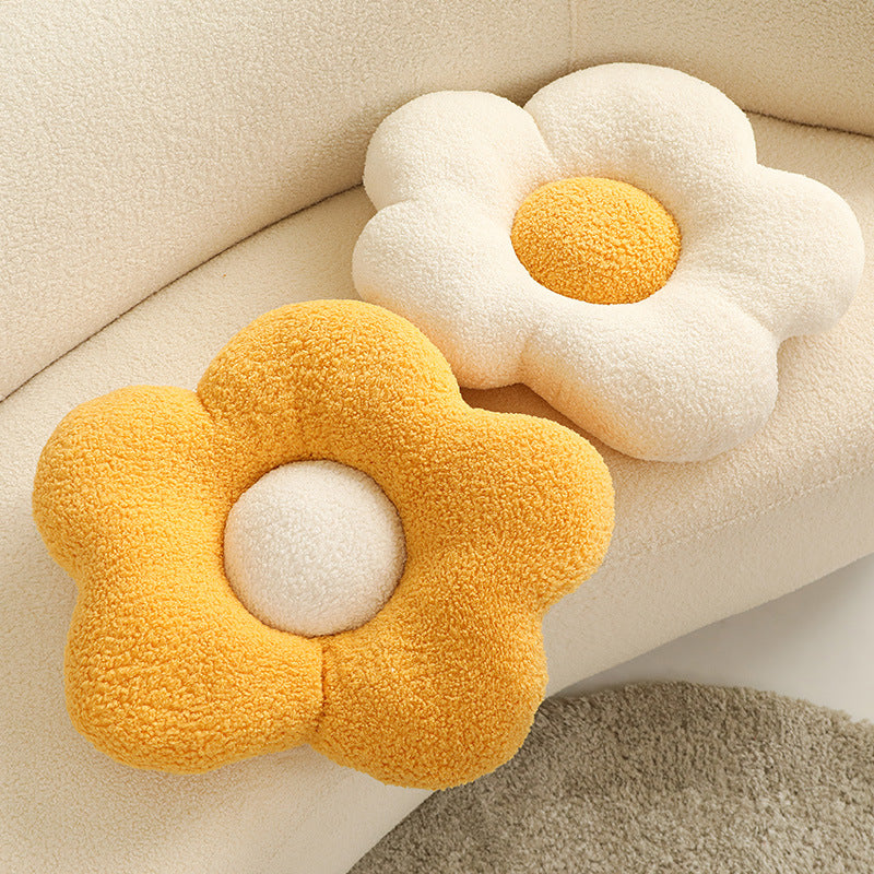 Two fluffy flower-shaped cushions: one yellow with a cream center, one cream with a yellow center.