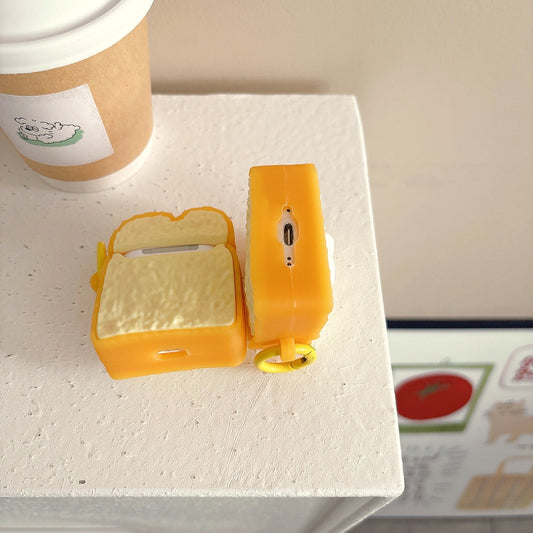 Toast AirPods case open beside a closed one on a white table next to a coffee cup