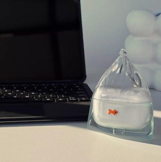 Lake blue goldfish in a bag AirPods case with a small orange fish, on a desk