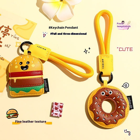 Two leather keychains with yellow wrist straps: a smiling burger and a sprinkled chocolate donut.
