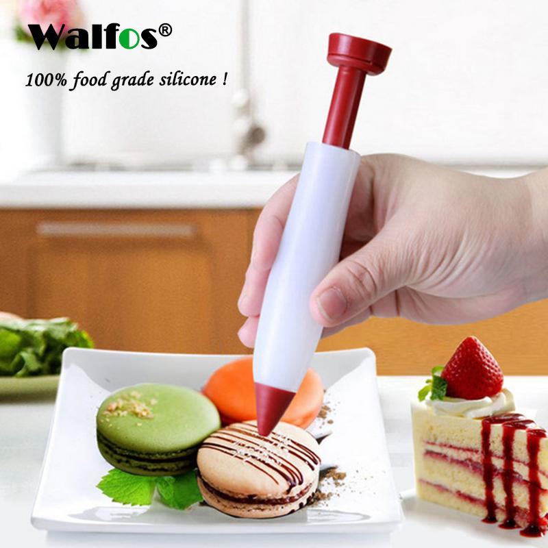 Red chocolate decorating writing pen held above macaroons on a plate, designed for precise chocolate application.