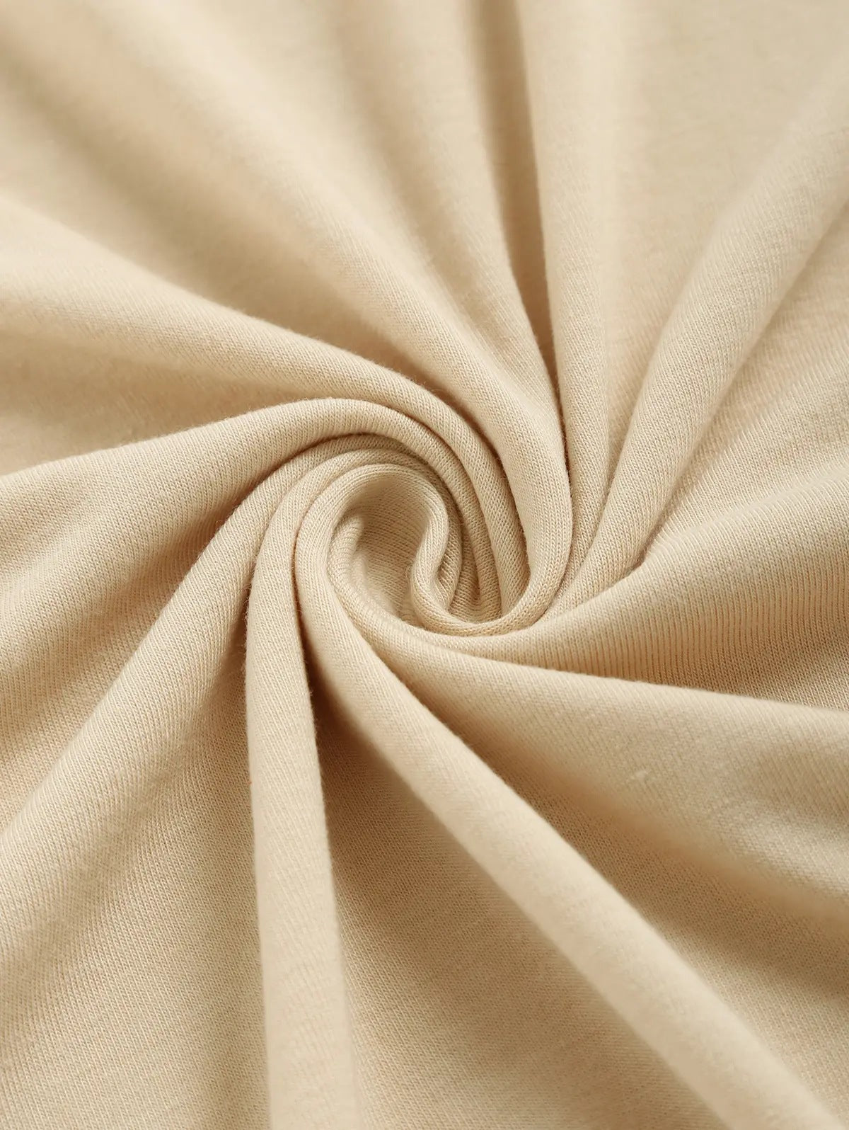 One beige knit fabric swirled into a spiral, showing fine ribbed texture.