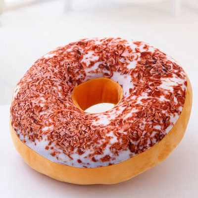 One round donut-shaped plush pillow with white icing, brown sprinkles and tan sides, lying flat.