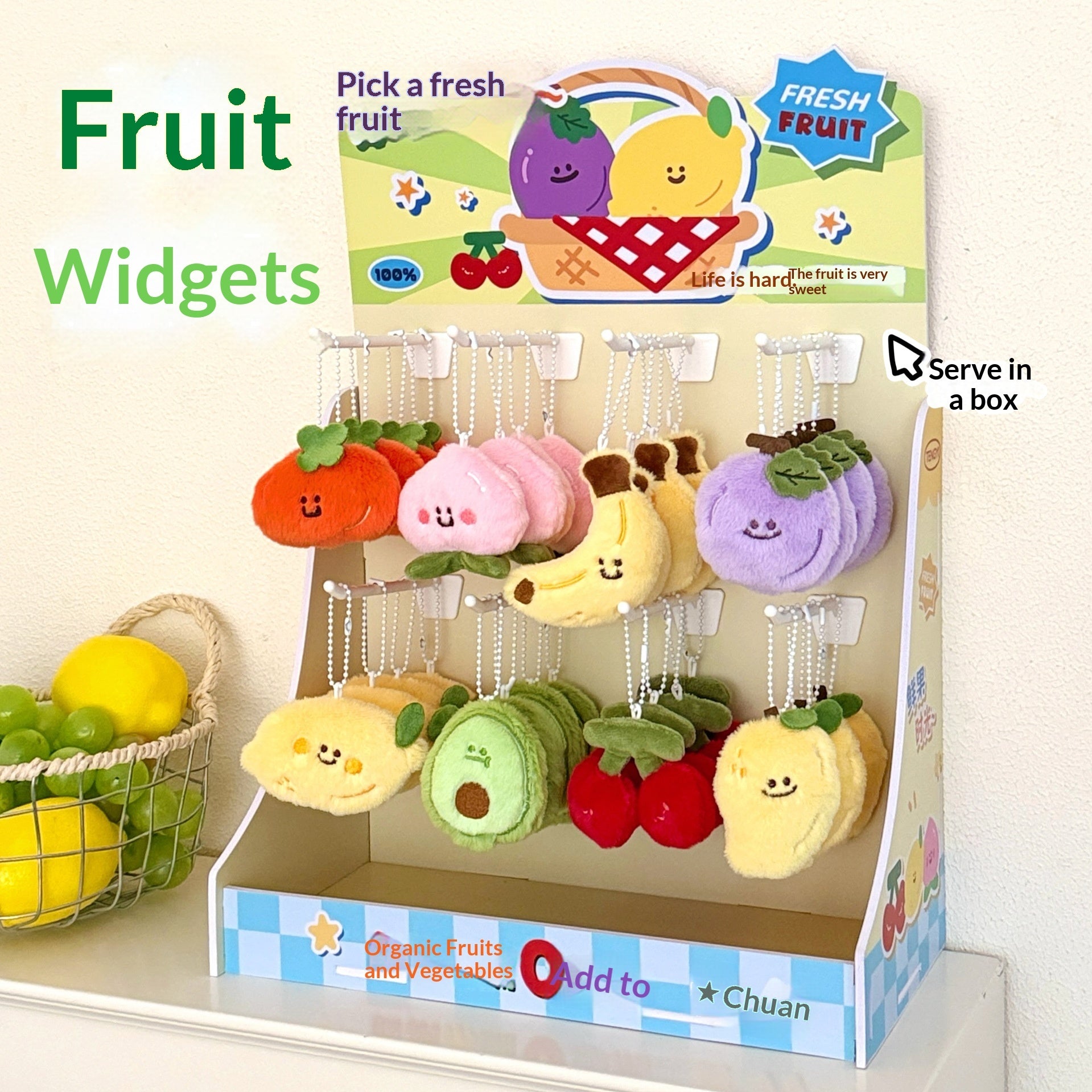 Cardboard display holding 20 small plush fruit keychains on silver ball chains, each a colored smiling fruit.