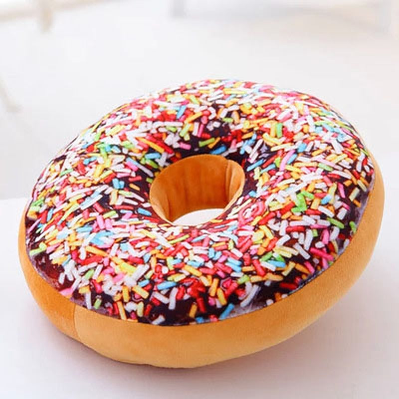 One donut-shaped plush pillow with tan base, chocolate-top print, multicoloured sprinkles and central hole.