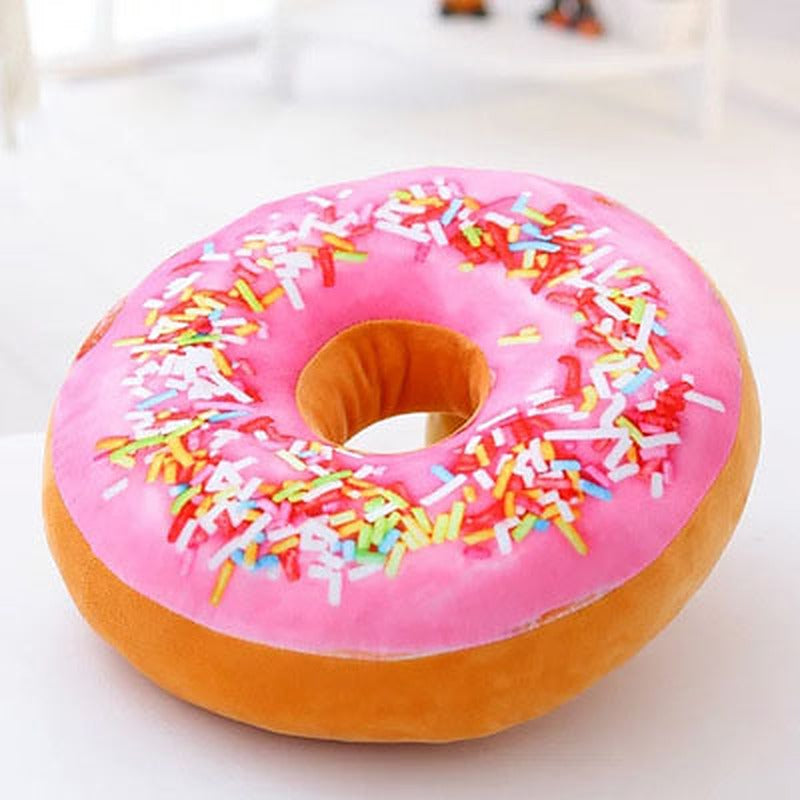 One round donut-shaped plush pillow with pink frosting, multicoloured sprinkles and tan base.