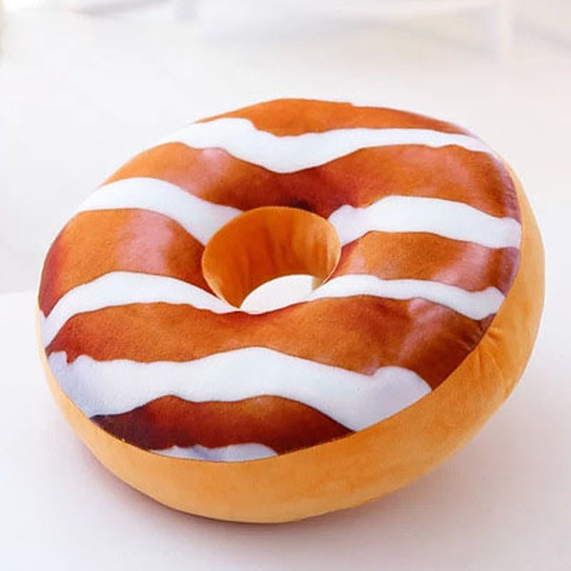 One round donut-style plush pillow, golden-brown with white wavy icing stripes and centre hole on white.