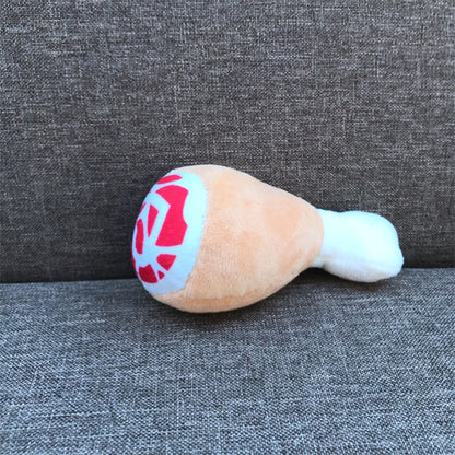 One plush chicken drumstick toy, tan body with white bone end and blue circle with red pattern, on gray sofa.