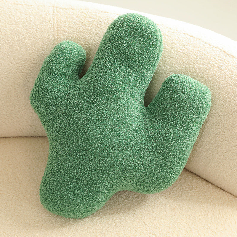 One green boucle cushion shaped like a three-lobed cactus on a cream boucle chair.
