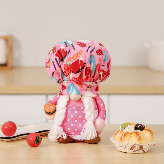 One pink plush doll with large patterned chef hat, white braided yarn hair, wooden nose and tiny hamburger.