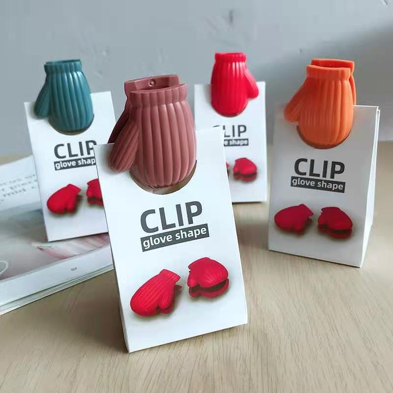 Four mitten-shaped ribbed clips (mauve, teal, red, orange) on white 'CLIP glove shape' cards.